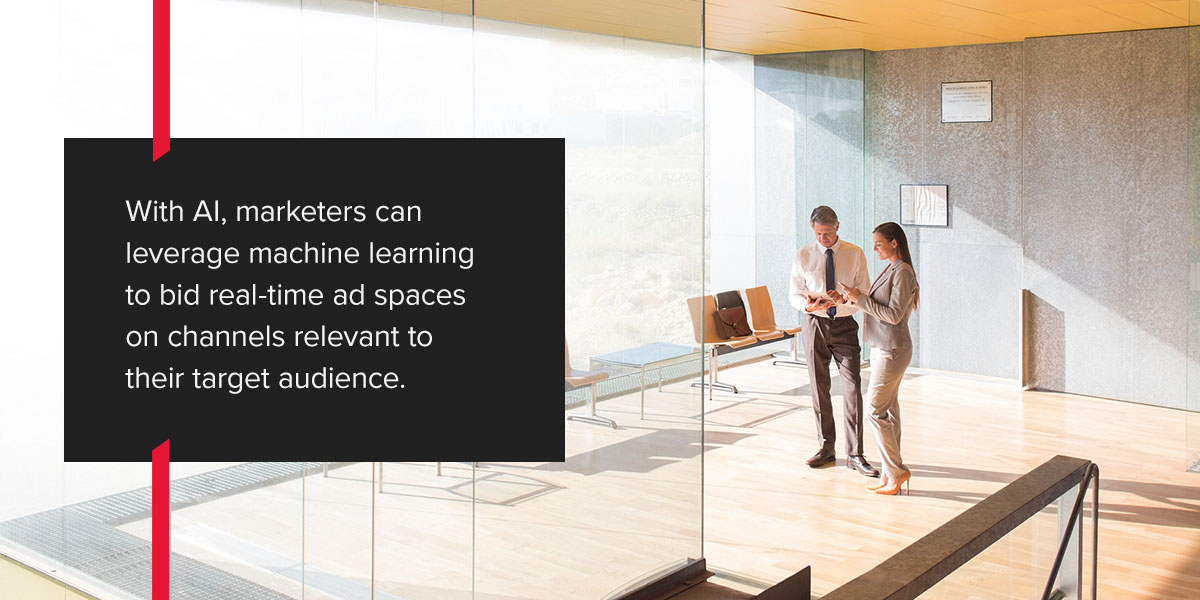 With AI, marketers can leverage machine learning to bid real-time ad spaces on channels relevant to their target audience. Two people discussing in a bright room.